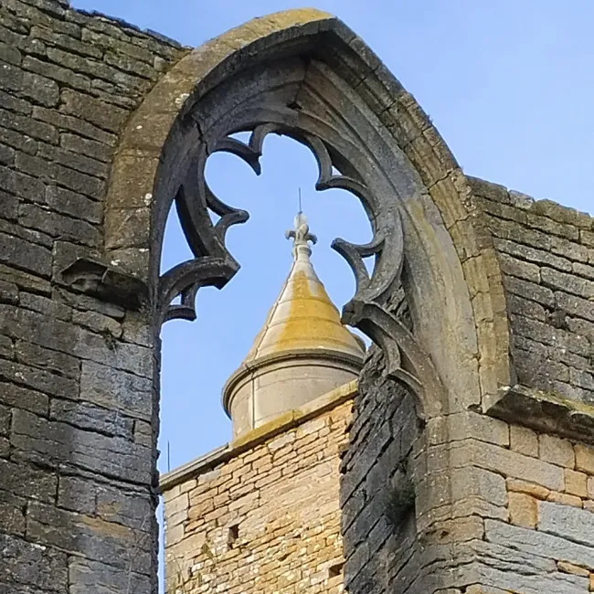 Le donjon à travers une baie gothique du logis de Beaujeu